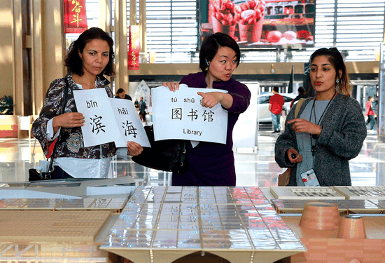 Hager Braham from Canada (left) and Jyotika Chauhan (right) from South Africa learn Chinese while visiting Binhai Cultural Center during a language program launched by a community school in the Tianjin Economic-Technological Development Area. (JIA CHENGLONG/FOR CHINA DAILY)