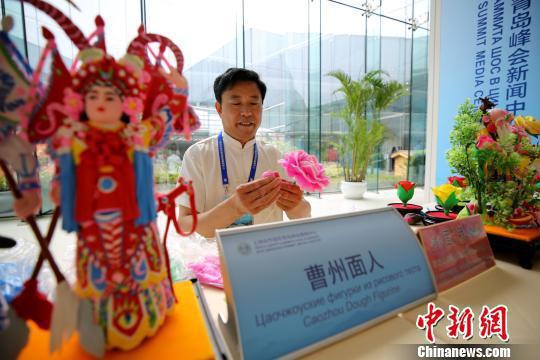 Dough figurine inheritor Mu Xujian displays his artwork at the press center of the Shanghai Cooperation Organization. (Photo/China News Service)