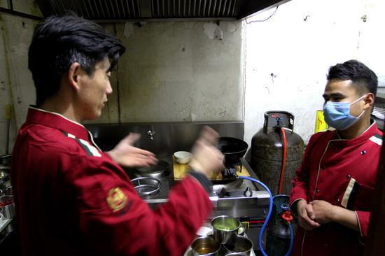 Liang communicates with a chef by sign language. (Photo by Zheng Tao/For China Daily)