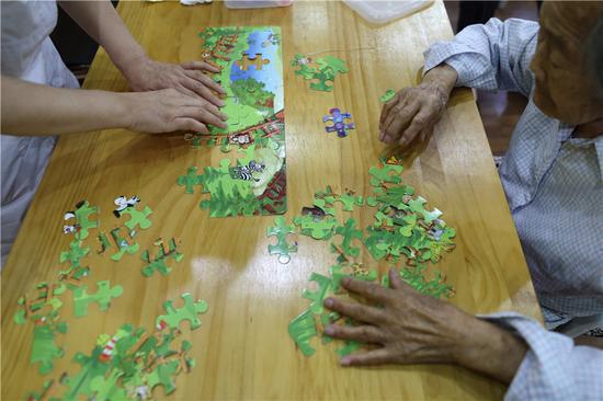 Seniors at Songtang play with a jigsaw puzzle. (Photo: China Daily/Wang Jing)