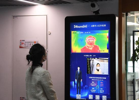 A staff member introduces an AI digital infrared thermometer at a building in Beijing, capital of China, March 16, 2020. (Xinhua/Ren Chao)