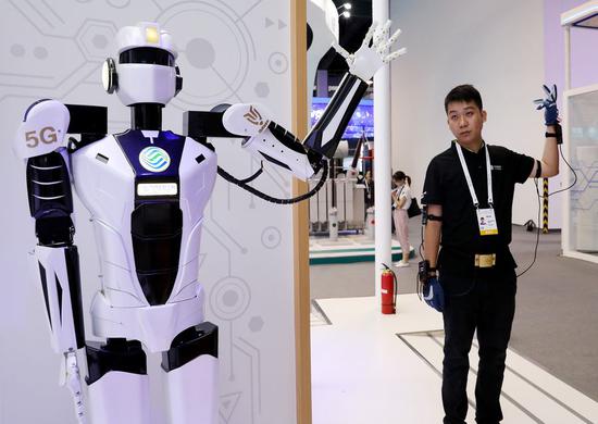 A staff member (R) demonstrates 5G-based remote control of a robot during the 2019 World Artificial Intelligence Conference (WAIC) in east China's Shanghai, Aug. 29, 2019. (Xinhua/Fang Zhe)