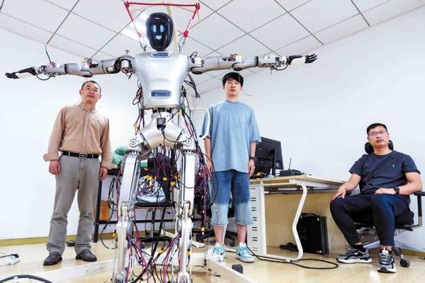 Liu Lizheng (left), head of humanoid robot projects at Shanghai's Fudan University, and his colleagues pose with the Guanghua No 1 humanoid robot, which was developed by his team for elderly health care scenarios, on May 14. GAO ERQIANG/CHINA DAILY