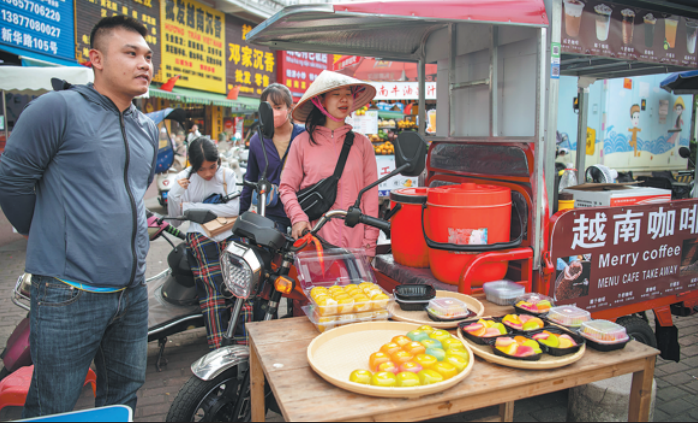 A young couple from Vietnam sell fruit pastries and Vietnamese coffee in Dongxing, Guangxi Zhuang autonomous region, in April. Cross-border trade has thrived in the small city, which borders Vietnam's Mang Cai. ZHAI LIQIANG/CHINA NEWS SERVICE
