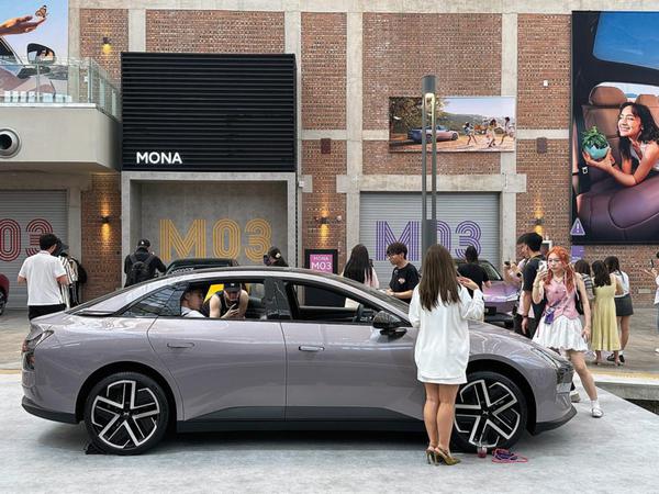Visitors take pictures of an XPeng Mona M03 at an event on May 28 in Beijing. Photo/CHINA DAILY
