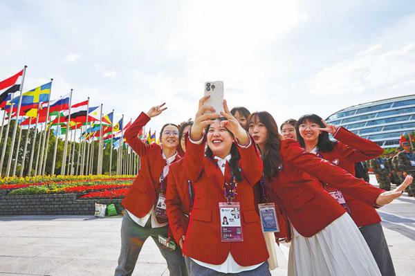  Volunteers of the upcoming 8th China International Import Expo take a selfie at the National Exhibition and Convention Center in Shanghai on Monday. SHI JUE/FOR CHINA DAILY