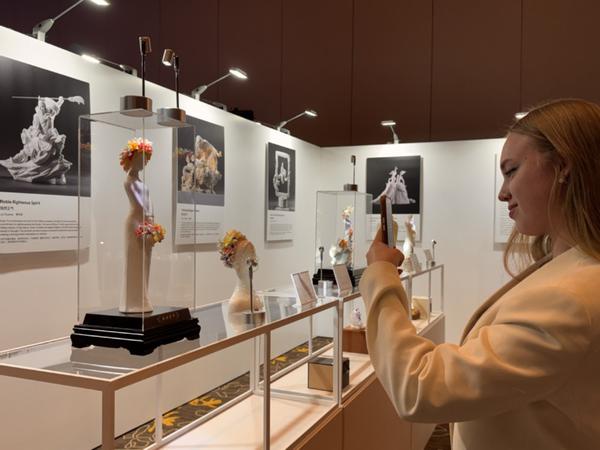  A visitor photographs an artwork at an exhibition showcasing China's Dehua white porcelain in San Gabriel, California on Nov 21. [RENA LI/CHINA DAILY]