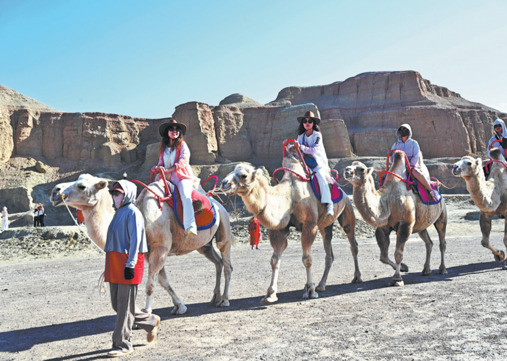 Tourists enjoy a camel ride in the Gobi Desert, in the Xinjiang Uygur autonomous region's Karamay. Photo/CHINA DAILY