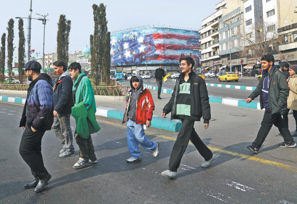 &nbsp;People walk past a billboard depicting a damaged US aircraft carrier in Tehran on Sunday. XINHUA