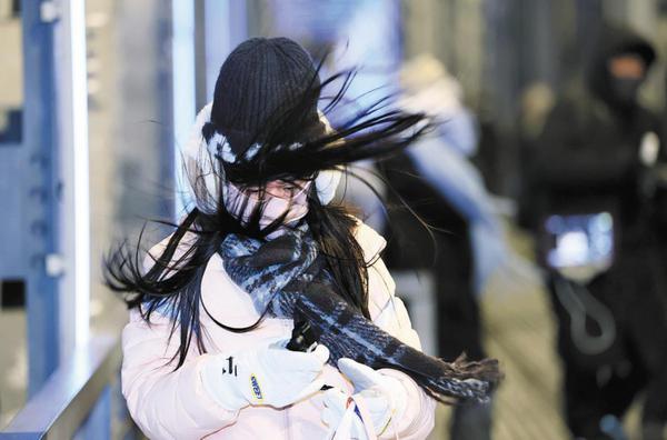 A resident braves strong winds while crossing a bridge in Harbin, Heilongjiang province, on Thursday, as the perceived temperature drops to minus 30 C. （Photo: Zhang Shu/ China Daily)