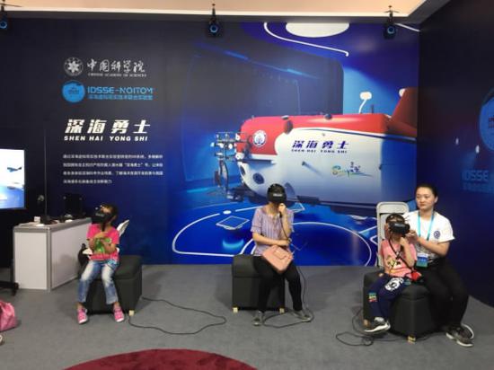 Attendees watch China's deep-sea manned submersible through VR glasses. /Photo via ST Daily