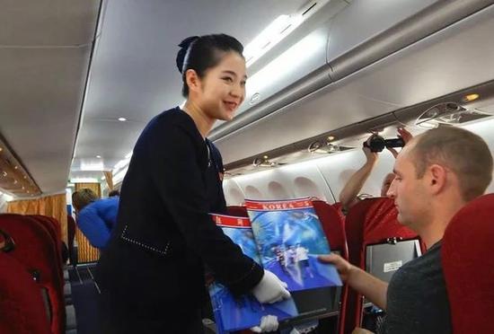 A crew member shows a magazine to a foreign journalist on a plane carrying reporters to the DPRK to watch the closure of a nuclear site on May 22, 2018. /CCTV Photo