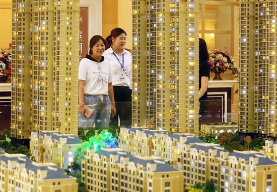 A saleswoman (center) talks with customers at a real estate sales office in Huai'an, East China's Jiangsu province. (Photo: Zhou Changguo/China News Service)