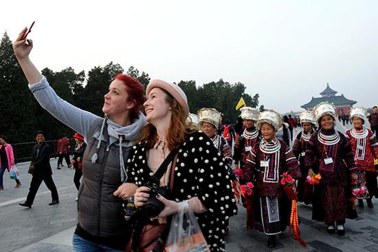Two foreign tourists take pictures in Beijing's Temple of Heaven.  (File photo/China Daily)