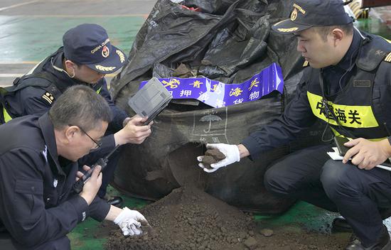 Customs officials examine solid waste in Qingdao, Shandong province, on Tuesday. Qingdao customs officials busted three groups and held 13 suspects involved in smuggling cases the day after a national crackdown began. (Zhang Jingang/For China Daily)
