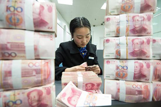 A clerk counts cash at a bank outlet in Hai'an county, East China's Jiangsu Province. (Photo/China Daily)