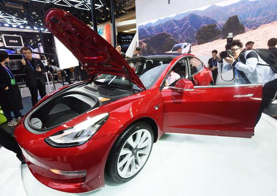 Visitors take photographs of a Tesla electric car at a recent automobile exhibition held in Beijing. (Photo by Long Wei/For China Daily)