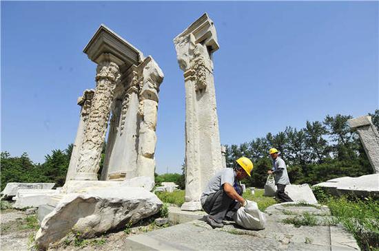 Workers pull weeds at the Yuanying Guan ruins at Yuanmingyuan, or Old Summer Palace, in preparation for a project to preserve the standing pillars. Photo by Yuan Yi/For China Daily