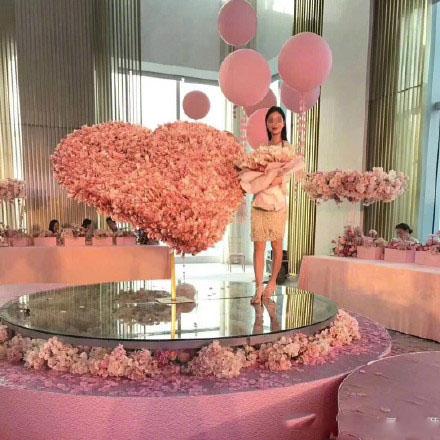 A young woman poses with a large heart-shaped bouquet decorated with bundles of bank notes. (Photo/Chongqing Morning Post)