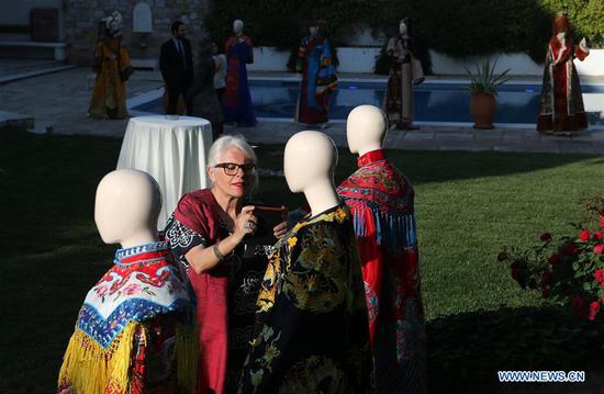 A woman takes photos of Chinese opera costumes during a donation ceremony in Athens, capital of Greece, on May 23, 2018. The Chinese embassy in Athens donated a collection of 22 Chinese opera costumes to Greece in a ceremony held in Athens on Tuesday. (Xinhua/Marios Lolos)