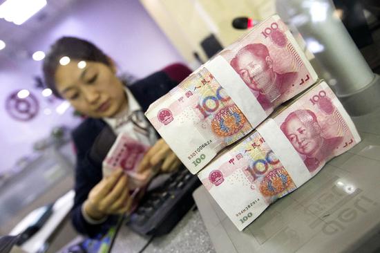 A cashier at a bank in Taiyuan, Shanxi province, counts renminbi notes. (Photo: China News Service/Zhang Yun)