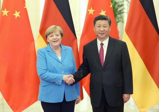 President Xi Jinping greets German Chancellor Angela Merkel at the Great Hall of the People in Beijing on Thursday. In their meeting, Xi welcomed Germany to seize the opportunities available as a result of China’s new round of opening-up. (Photo by Wu Zhiyi/China Daily)