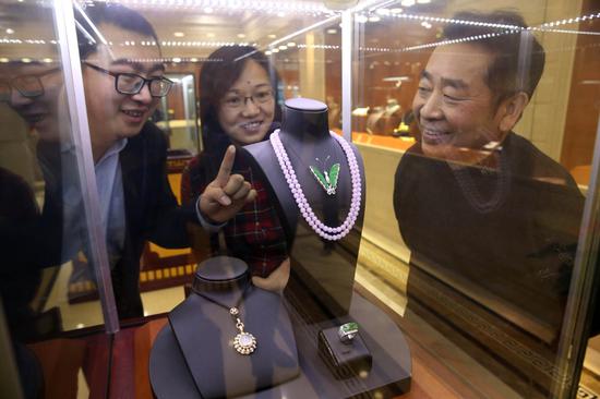 Visitors watch a violet jade pendant at a jewelry fair held in Beijing. (Photo by Chen Xiaogen/For China Daily)
