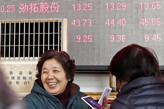 An investor smiles after checking share prices at a securities brokerage in Shanghai. (Photo/China News Service)