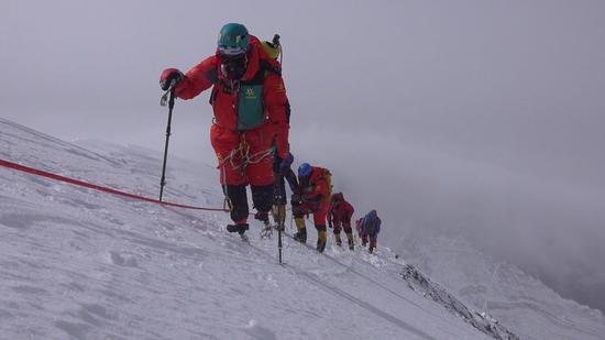 Xia Boyu, wearing an oxygen mask, labors upward Mount Qomolangma in May. (Photo/China Daily)