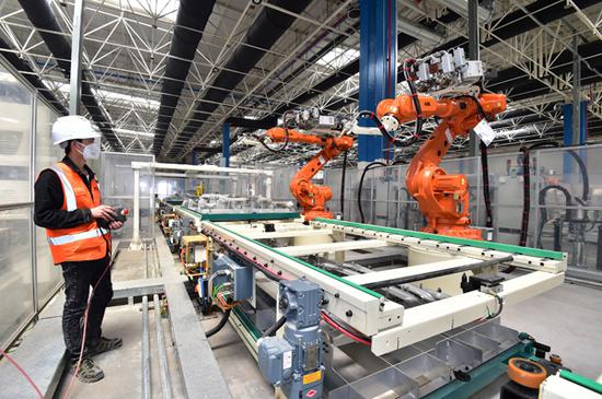 A technician adjusts the arms of robots at a new energy vehicle manufacturing plant in Yiwu, Zhejiang province. (Photo by Lyu Bin/For China Daily)