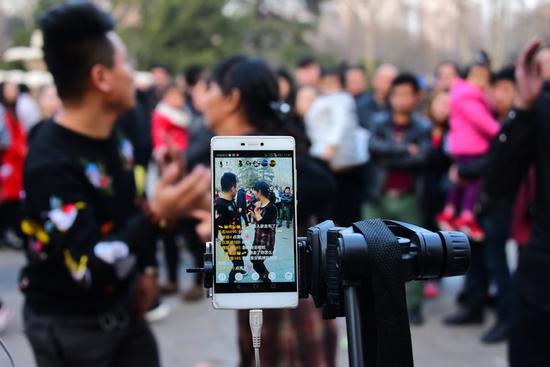 People performing a square dance are livestreamed on Kuaishou at the People's Park in Zhengzhou, capital of Central China's Henan  Province.  (Photo by Li Sixin/For China Daily)