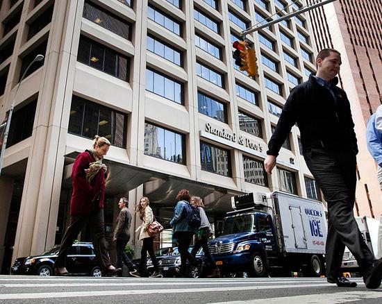 Pedestrians cross the street in front of the Standard & Poor's Financial Services LLC building in New York.  (Photo provided to China Daily)