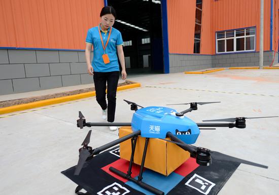 An employee of Cainiao Network, the logistics arm of Alibaba, receives a delivery from a drone at a storage facility in Xi'an, capital of Shaanxi province. (Photo/Xinhua)