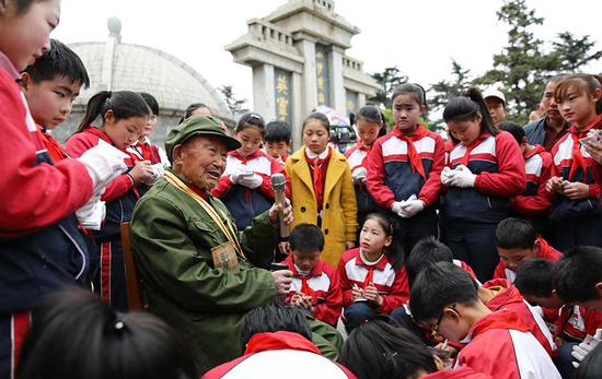 Ma Ruying, a veteran who fought in the War of Resistance Against Japanese Aggression (1931-45), shares his memories about the war with students at a cemetery in Lianyungang, Jiangsu province, on April 5, Tomb Sweeping Day.  (Si Wei/For China Daily)