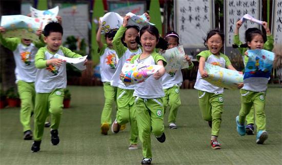 Kindergarten children show their paintings on Thursday to celebrate International Children’s Day, which is Friday, in Yangzhou, Jiangsu province. (MENG DELONG/FOR CHINA DAILY)