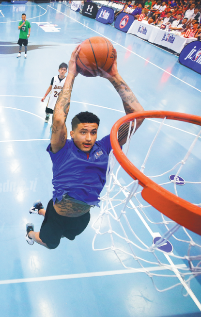 Kyle Kuzma of the Los Angeles Lakers shows Chinese students  how it’s done during an NBA Cares clinic, which took place on  the sideline of the Jr. NBA Beijing High School League Finals at  the Affiliated High School of Peking University in Beijing on  Saturday. (Photo/Provided to China Daily)