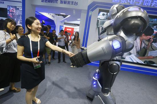 A visitor shakes an AI-powered robot's hand at the 5th China Beijing International Fair for Trade in Services on May 28. (CAO BOYUAN/FOR CHINA DAILY)