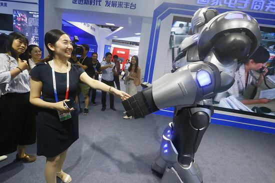 A visitor shakes an AI-powered robot's hand at the 5th China Beijing International Fair for Trade in Services on May 28.  (CAO BOYUAN/FOR CHINA DAILY)