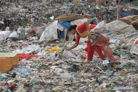 A woman collects plastic products at a dumping spot in Dhaka, Bangladesh, April 22, 2018. (Xinhua)