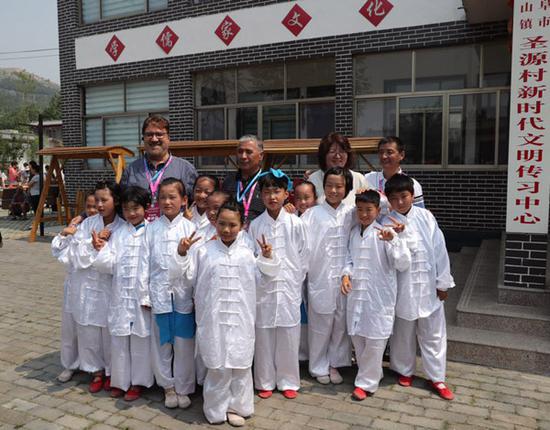 Ainura Temirbekova, deputy minister of culture, information and tourism of the Kyrgyz Republic, second from left, takes a group photo with young children in traditional Chinese costumes.  (Photo by Wang Qian/chinadaily.com.cn)