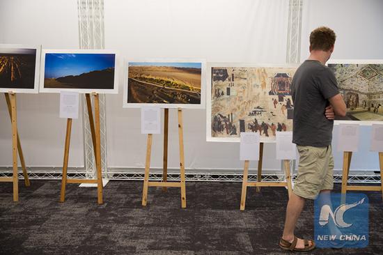 A visitor enjoys photos of mural paintings from Dunhuang caves, China in exhibition held in Tel Aviv's on June 4. (Xinhua/Guo Yu)