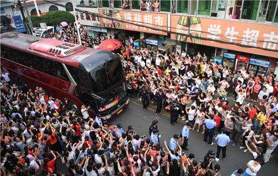 People wave goodbye on Tuesday to students on a bus who are about to take national college entrance exams in Lu'an, Anhui Province. The students were from Maotanchang Middle School in the city. (Photo/China News Service)