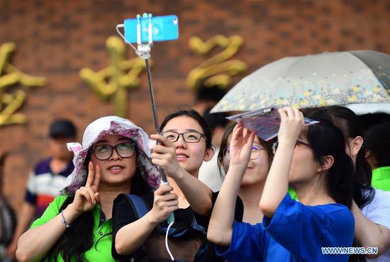 Examinees take a selfie with their family before the national college entrance examination outside an exam venue in Changchun, northeast China's Jilin Province, June 7, 2018. (Xinhua/Shen Bohan)
