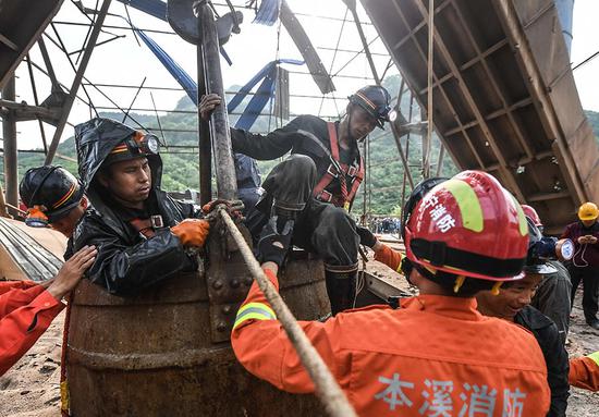 Rescued miners are lifted to safety at an iron ore mine in Benxi, Liaoning province, on Wednesday. A total of 23 trapped miners have been rescued and two others are unaccounted for after a blast at 4:10 p.m. on Tuesday. (Photo/Xinhua)
