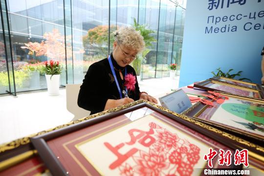 Li Wenling, a master of Chinese paper-cutting, shows her artwork at the press center of the Shanghai Cooperation Organization.  (Photo/China News Service)