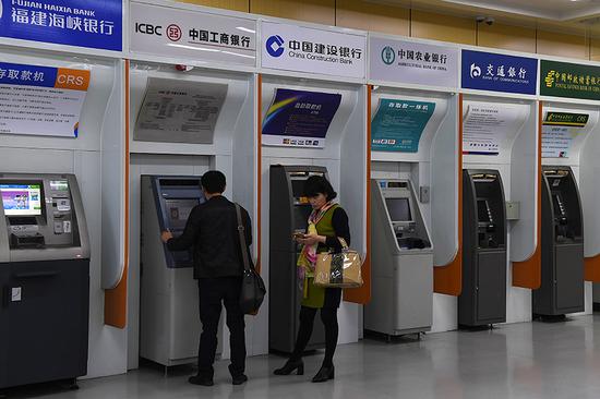 Customers of banks use ATMs at a public spot in Fuzhou, Fujian province. Shares of commercial banks fell on June 4, the first trading day after the PBOC announced changes to some monetary policy aspects on June 1. (Photo/China News Service)