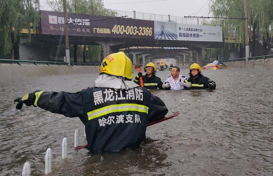 Firefighters evacuate people stranded by a sudden rainstorm on June 11, 2018 in Harbin, Heilongjiang Province. (Photo by Xiao Jinbiao / For China Daily)