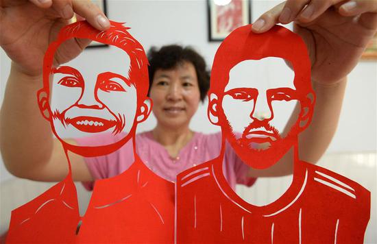 Craftswoman makes paper-cutting works to greet World Cup