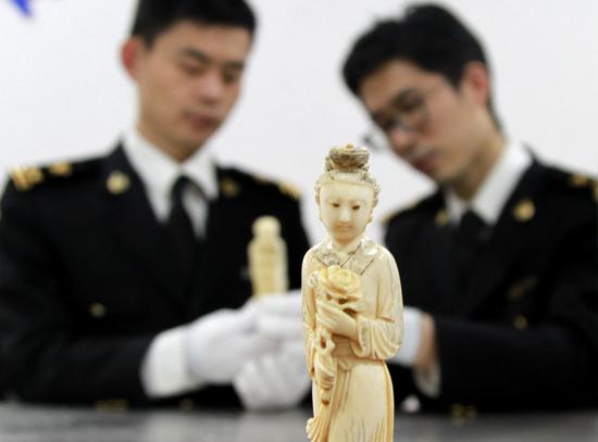Customs officers display a seized ivory figurine intercepted in a package from Europe in Qingdao, Shandong Province, in March. (Photo by ZHANG JINGANG/FOR CHINA DAILY)