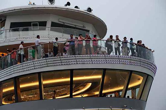 Tourists take in the sights as their cruiser navigates the Yangtze River. (Photo by Wang Zhuangfei/China Daily)